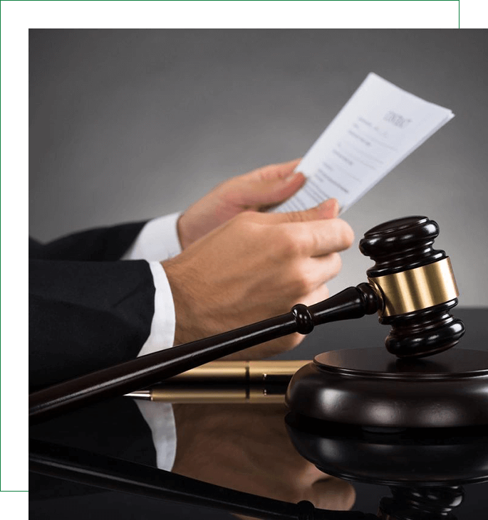 A judge holding papers and gavel on top of table.